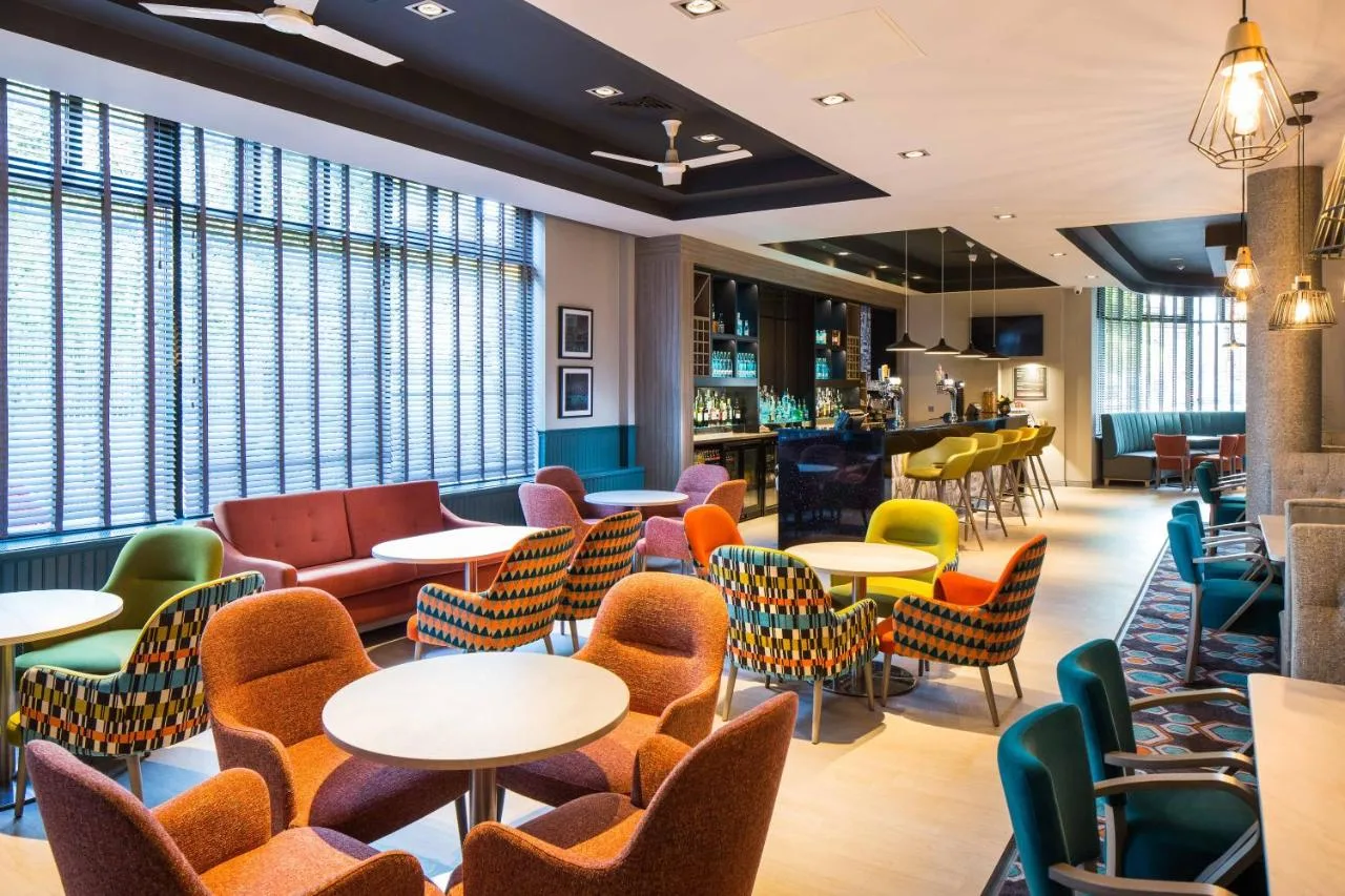 a restaurant with tables and chairs and a bar at Leonardo Hotel Belfast in Belfast
