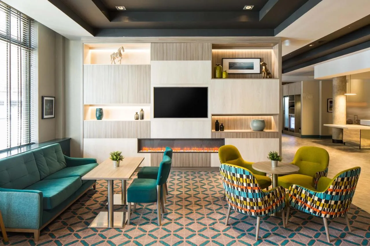 a lobby with a couch and chairs and a fireplace at Leonardo Hotel Belfast in Belfast