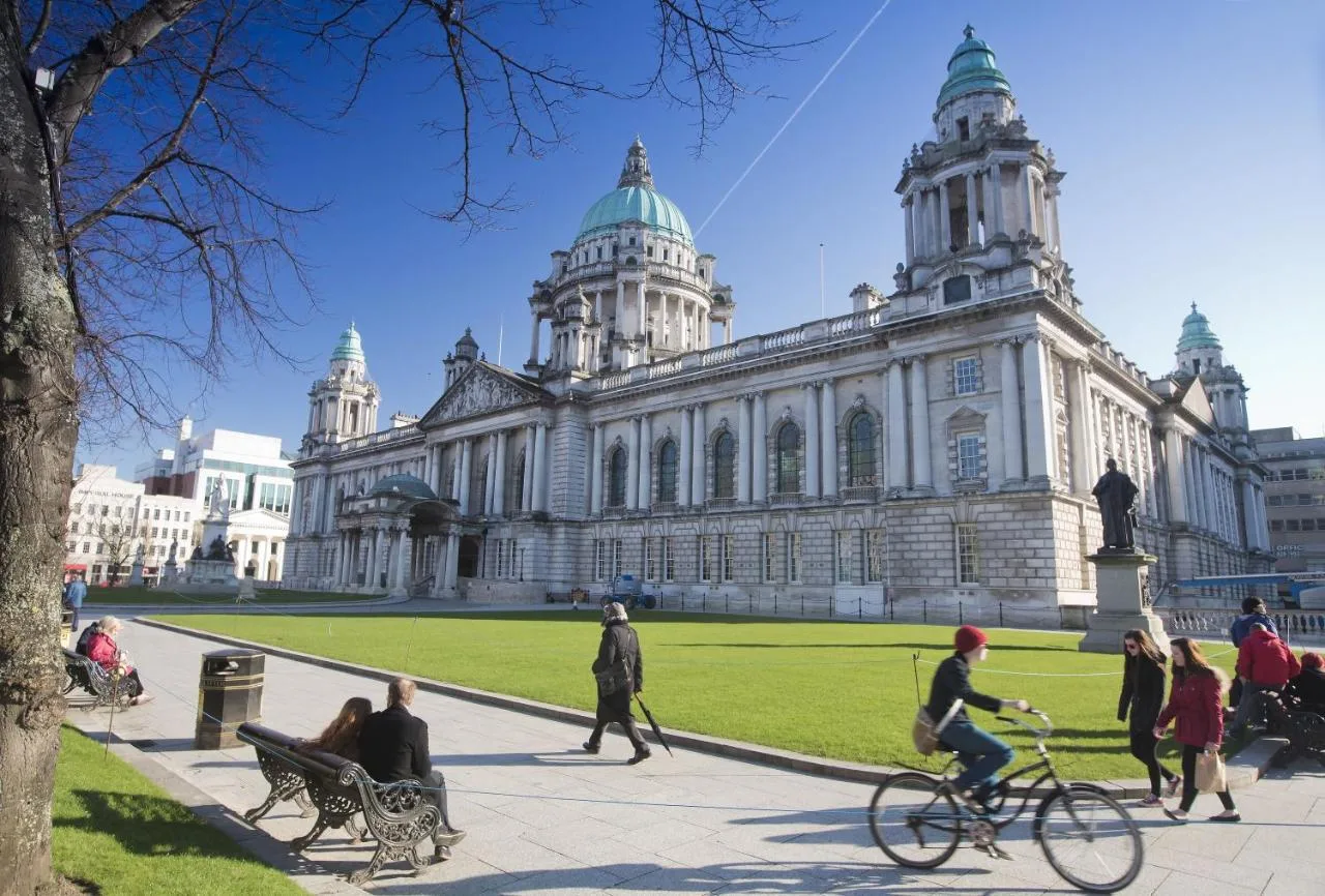 a group of people walking and riding bikes in front of a building at Leonardo Hotel Belfast in Belfast