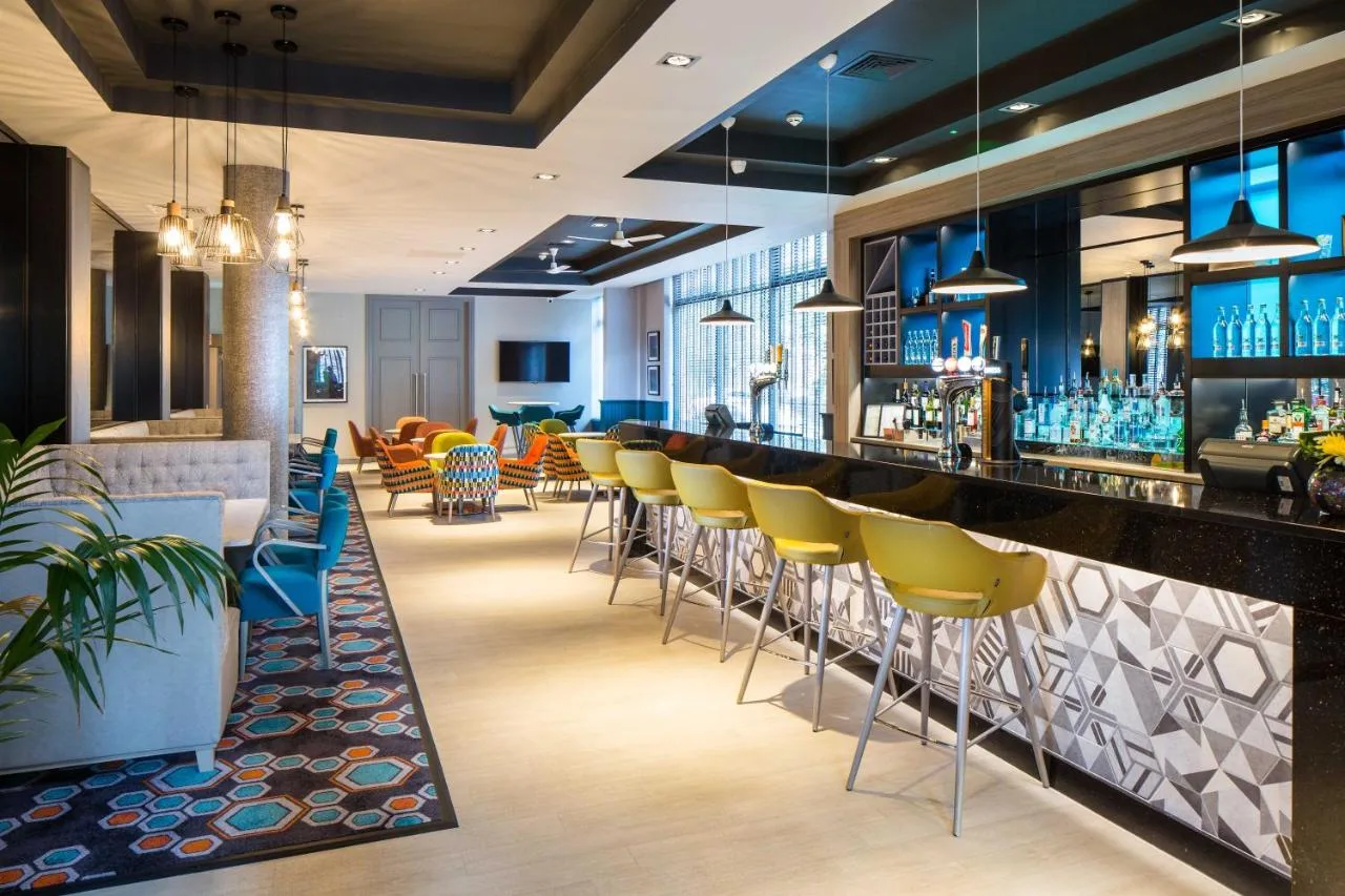 a bar with yellow chairs at a restaurant at Leonardo Hotel Belfast in Belfast
