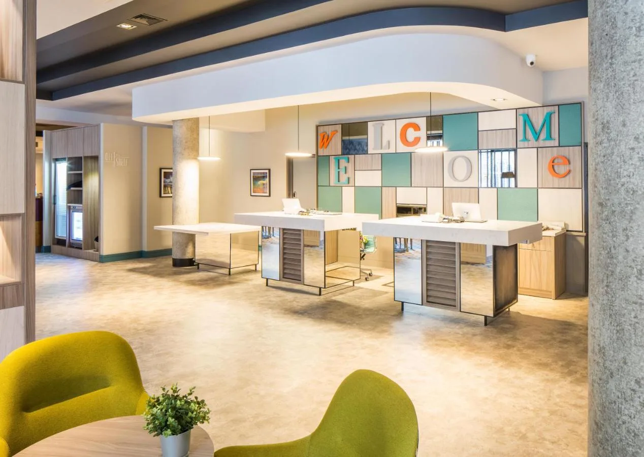 a lobby with tables and chairs in a building at Leonardo Hotel Belfast in Belfast